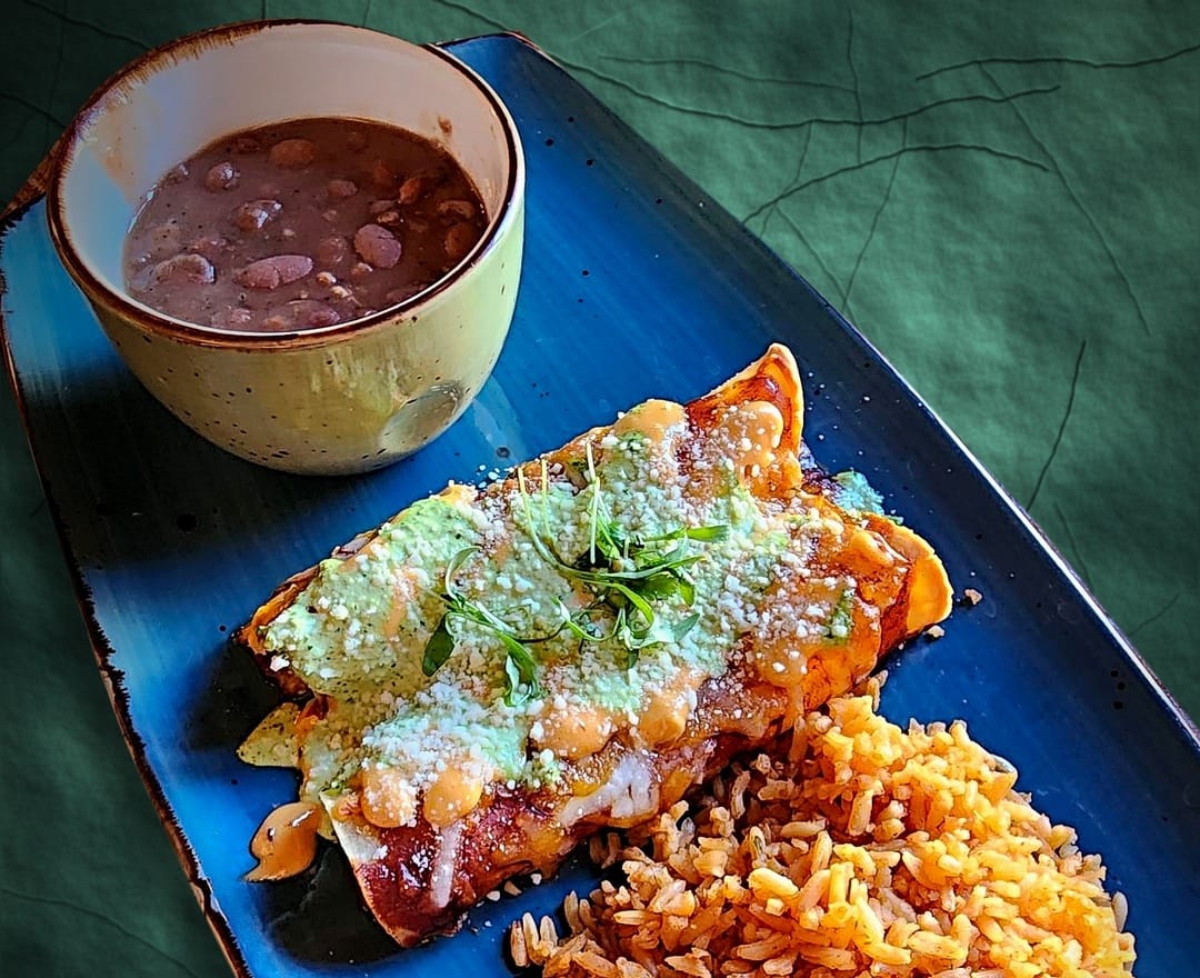 chicken enchiladas with Mexican rice and a cup of beans
